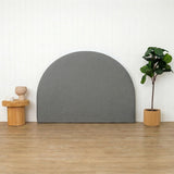 Grey arch-shaped headboard against a white wall with a wooden floor, small table, and plant.