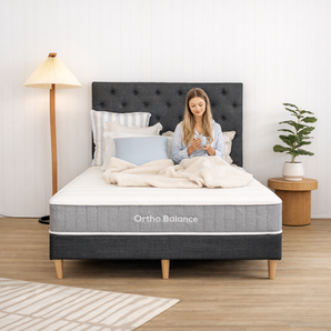 Women on Ortho Balance mattress holding a coffee cup with headboard and base.
