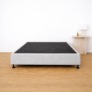 Light grey bed base on timber floor with side table