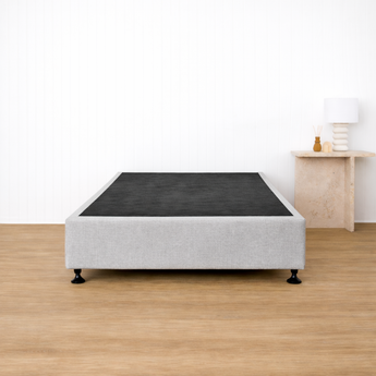 Naptime porto bed frame with black mattress on a wooden floor in a minimalistic room.