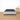 Naptime porto bed frame with black mattress on a wooden floor in a minimalistic room.