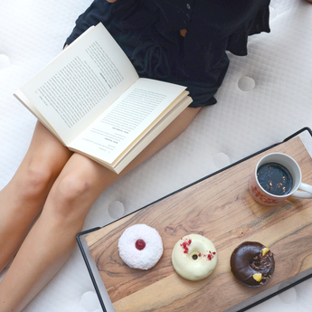 Women sitting on Optimal Support mattress with donuts and a coffee