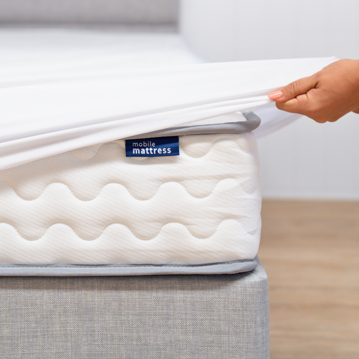 Hand pulling mattress protector over a mattress 