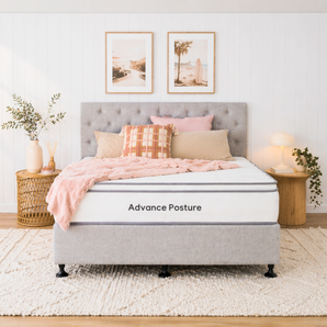 Gray upholstered bed with pink bedding and decorative pillows in a bedroom setting, featuring 'Advance Posture' branding.