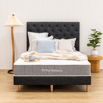 Bed with Ortho Balance mattress cover in a room setting with a lamp and plant.