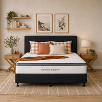 Bedroom with a bed featuring 'Optimal Support' mattress, plaid and solid color pillows, and a blanket.