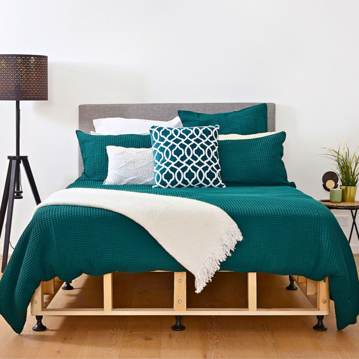 Scandi timber bed base with green and white linen and lamp