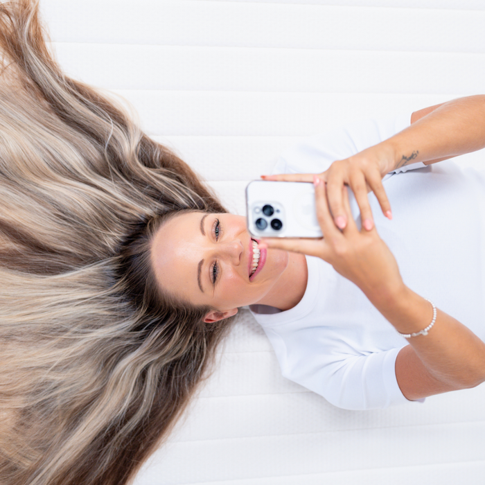 A girl laying on topper with hair spread out on her phone
