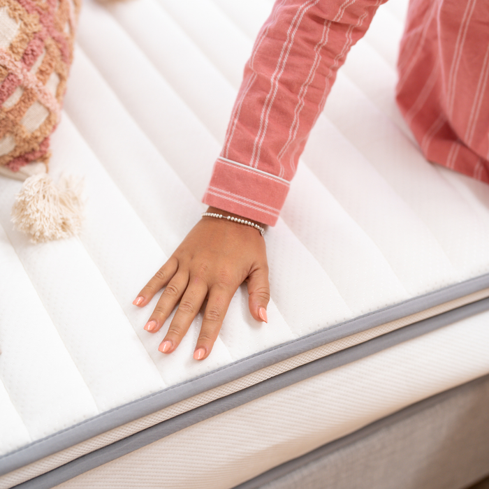 Hand touching a mattress to check its firmness