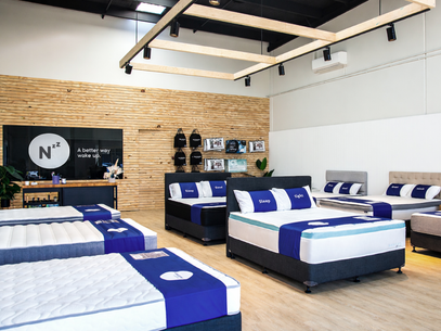 Mattress display in Naptime store with branded bedding and furniture.