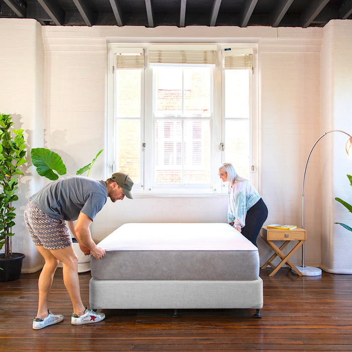 Bed base with mattress and couple adjusting the mattress